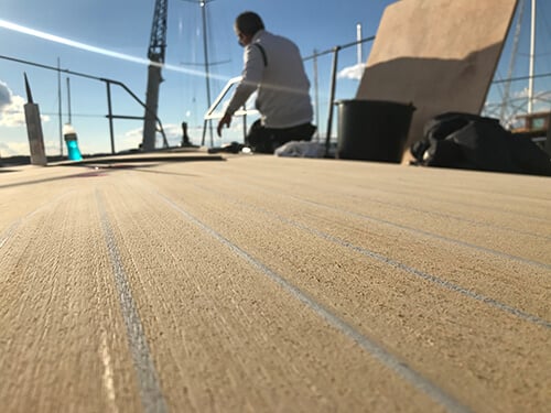 Flexiteek decking scrubbed with grey caulking being cleaned